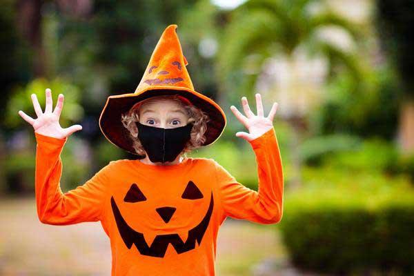 Child wearing a jack-o-lantern shirt and witch hat