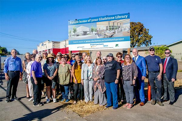 Elected officials and community members standing in front of the new sign in front of the location of the future Gladstone Library