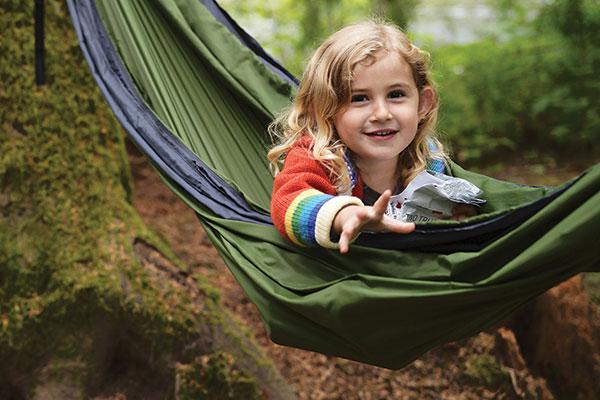 Little girl sitting in a hammock in a forest