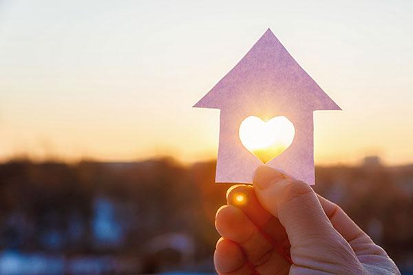 House with a carved heart on the background of sunrise.