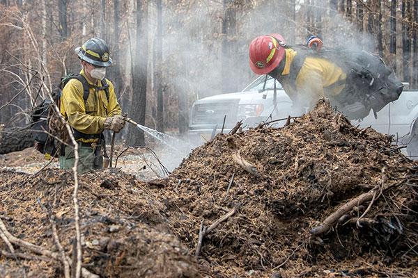 Firefighters with hoses putting out smoldering debris