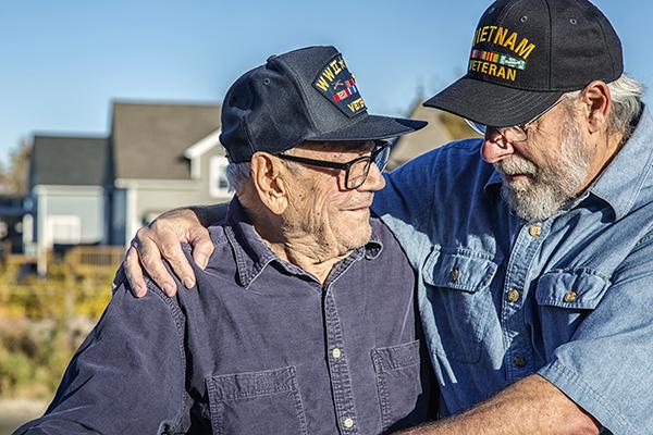 two senior veterans embrace in the sun