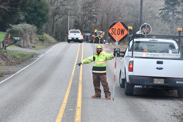 A traffic control flagger directs traffic through a work zone.