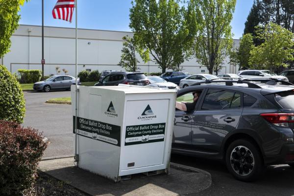 A voter returns their ballot from their car outside the elections office.