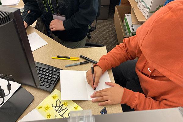 Children signing cards for survival kits