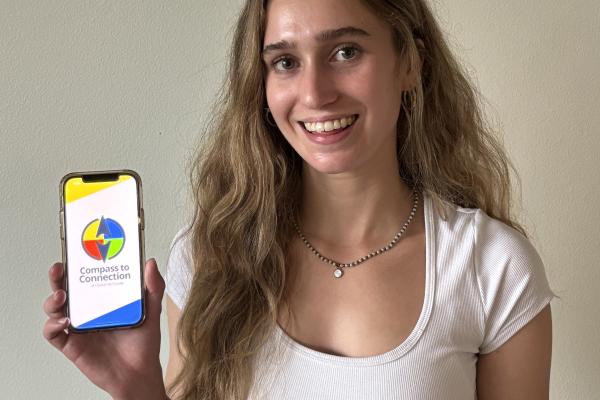 Young woman holding up phone featuring Compass to Connection app