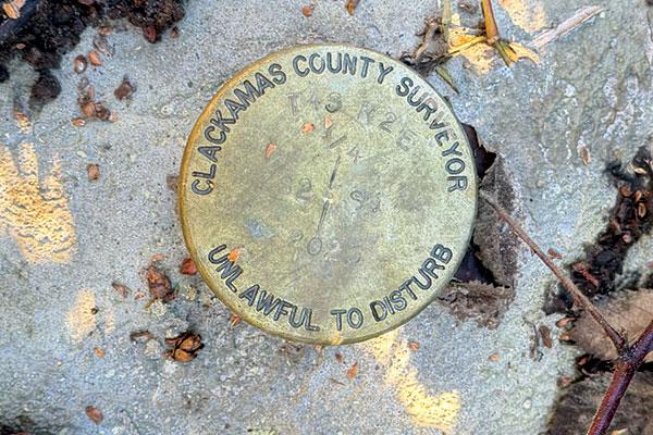 Brass disk representing a Clackamas County public land corner monument.