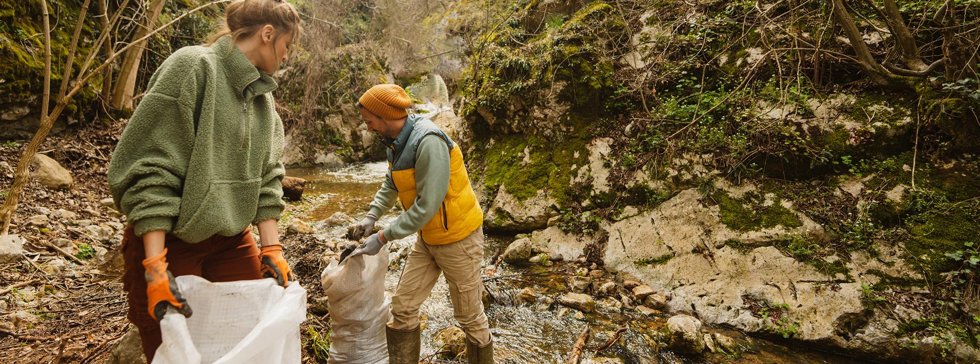 Two young people clean up a creek