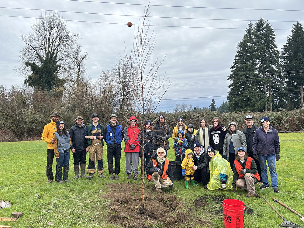 Volunteers standing together in front of newly planted tree